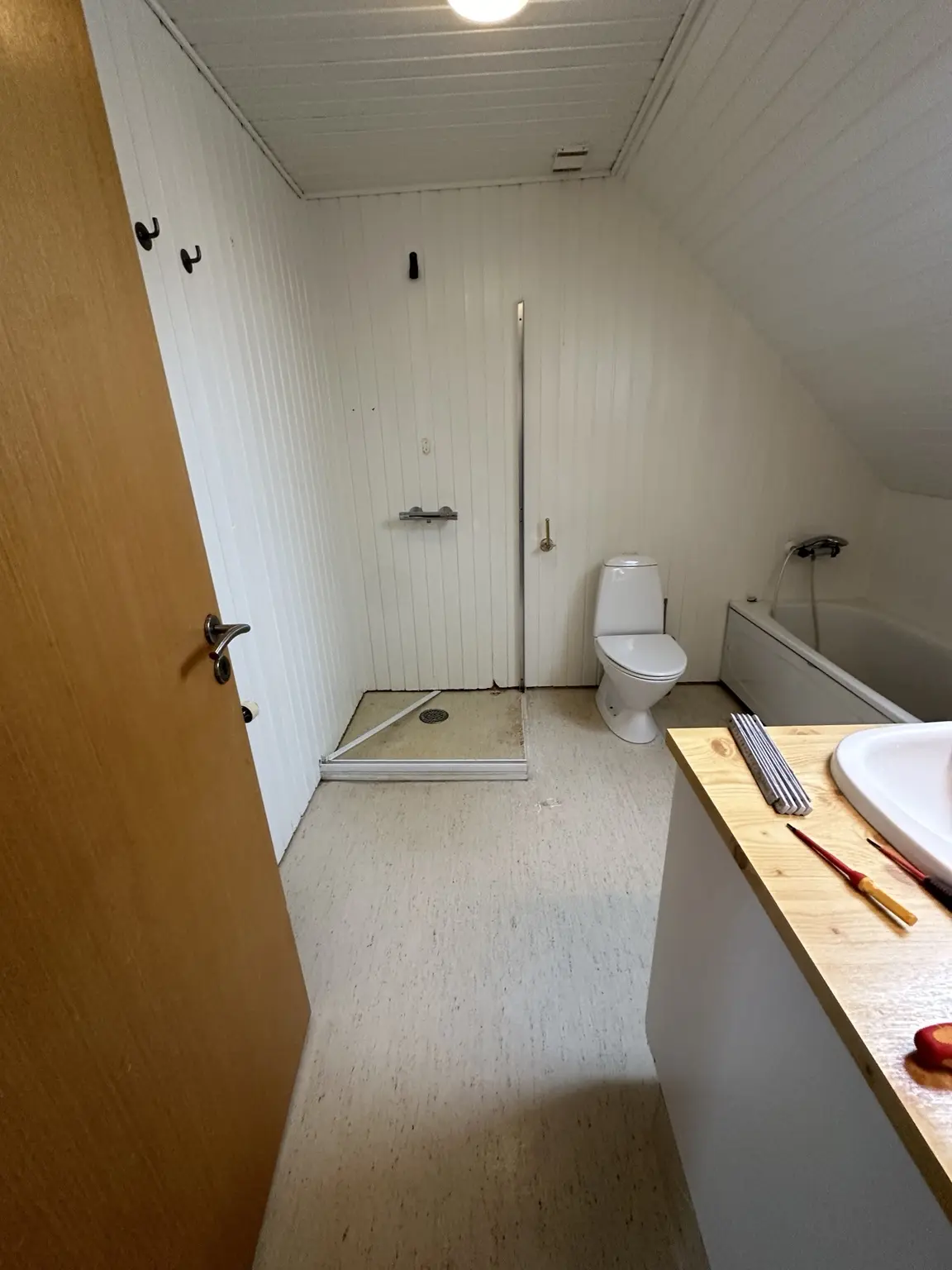 Badeværelset før makeover med ældre gulv og bruseområde